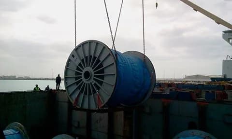 Large blue cable reel suspended above a vessel hold.