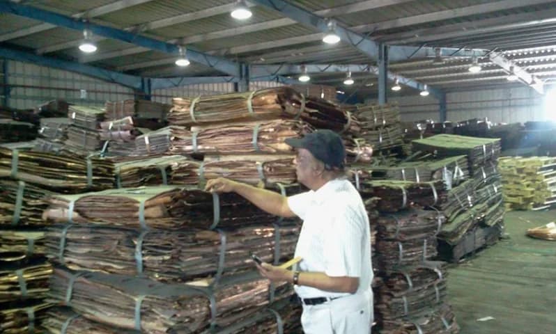 Surveyor inspecting bundled copper sheets.