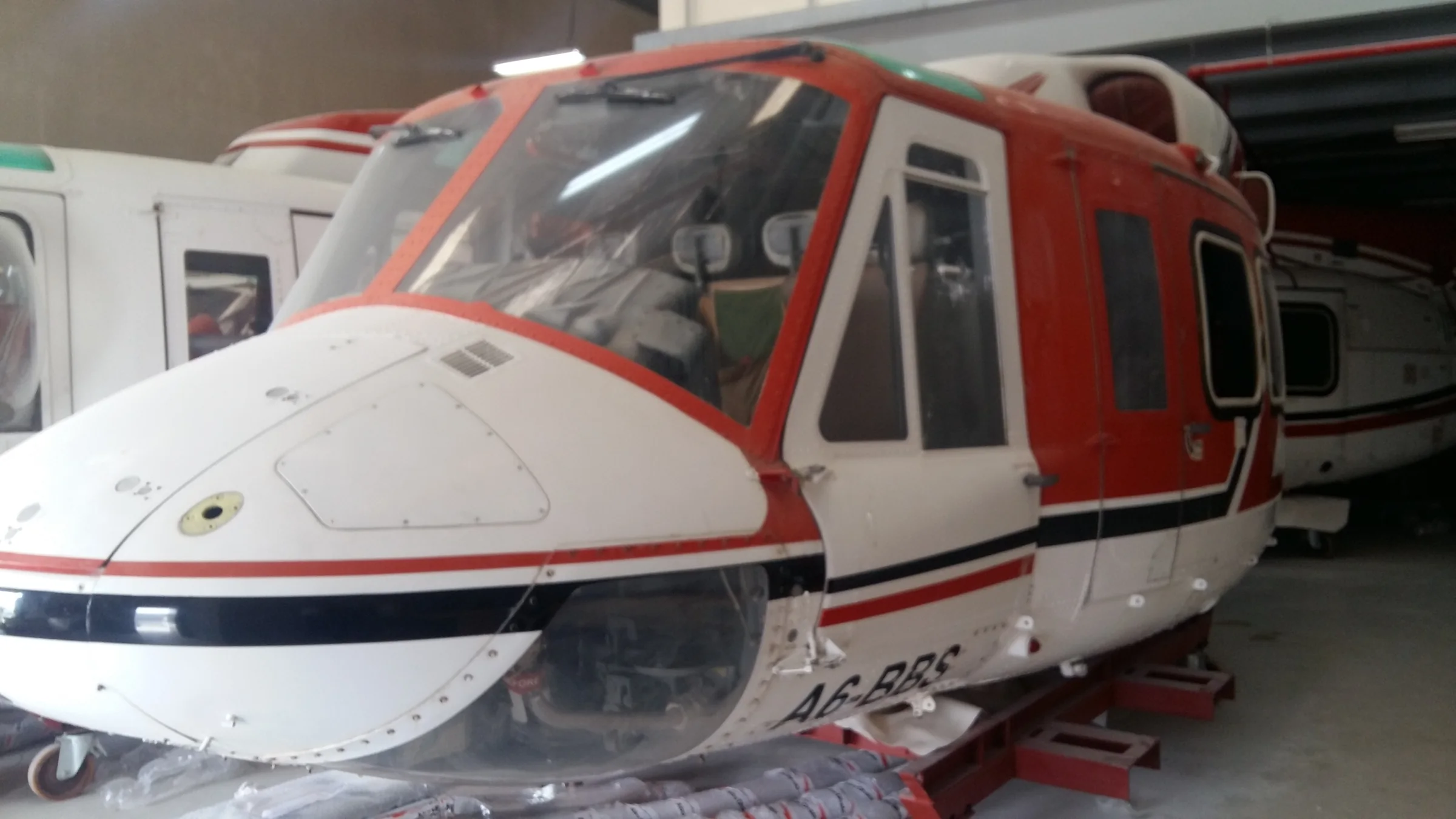 Close view of a red and white helicopter fuselage in storage.