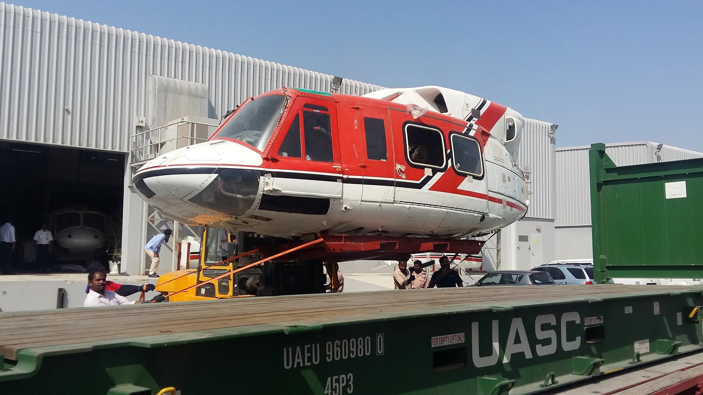 Red and white helicopter fuselage on a freight platform.