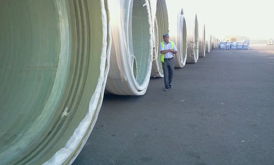 Surveyor beside a row of very large covered industrial coils.