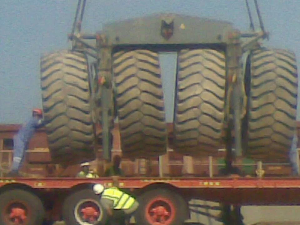 Large industrial tyres secured vertically on a flatbed trailer.