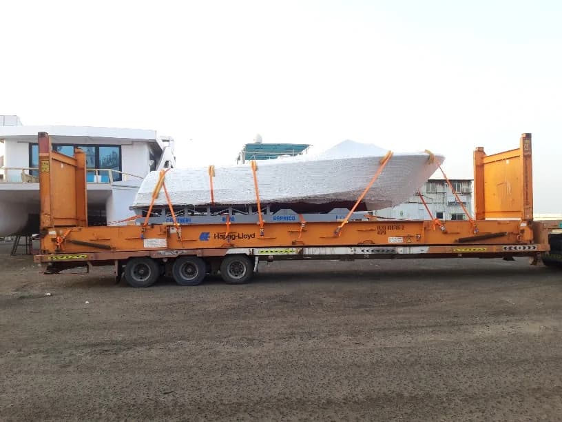 Wrapped boat strapped to a flatbed trailer.