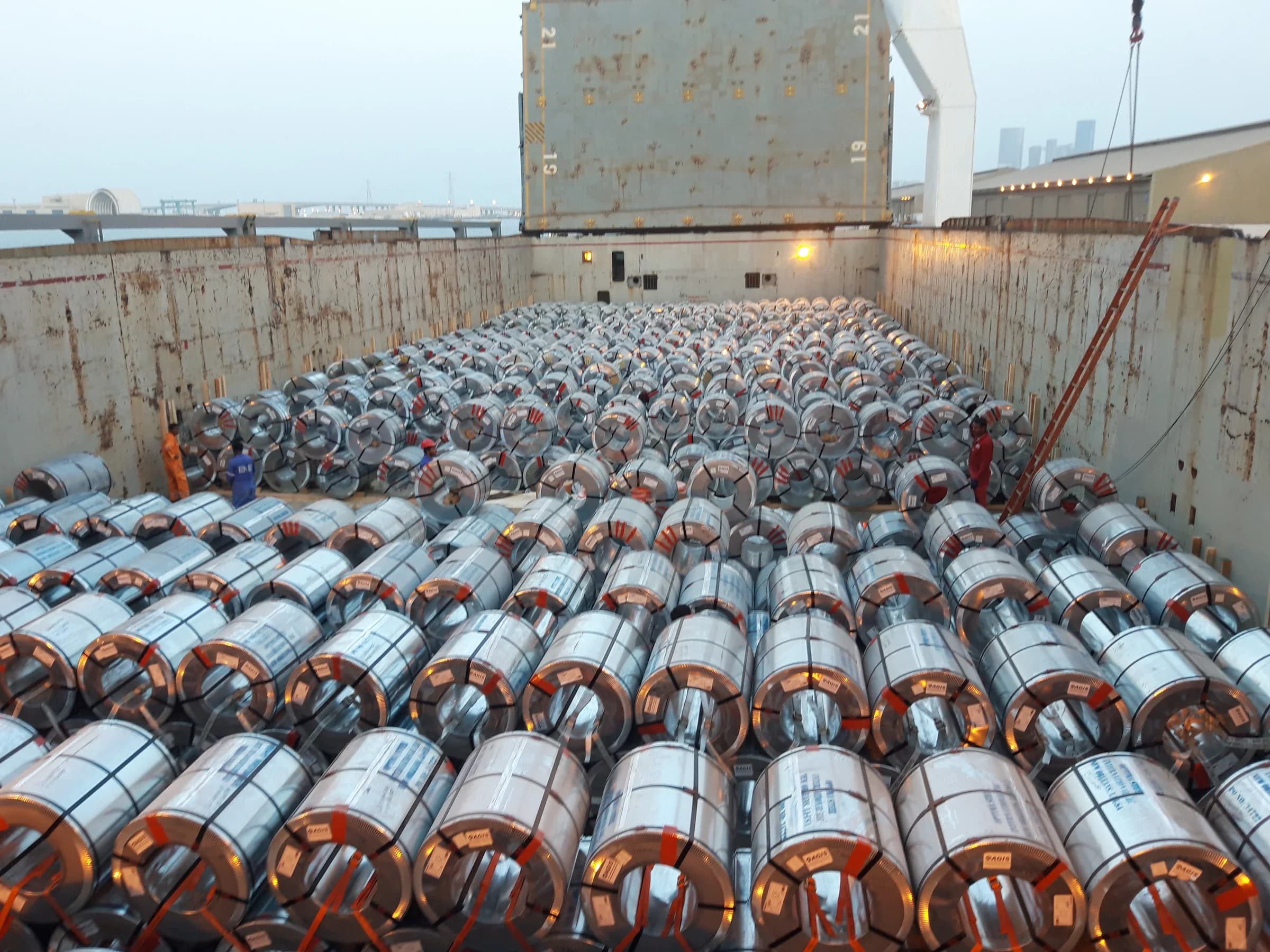 Steel coils packed in rows inside a ship's hold.