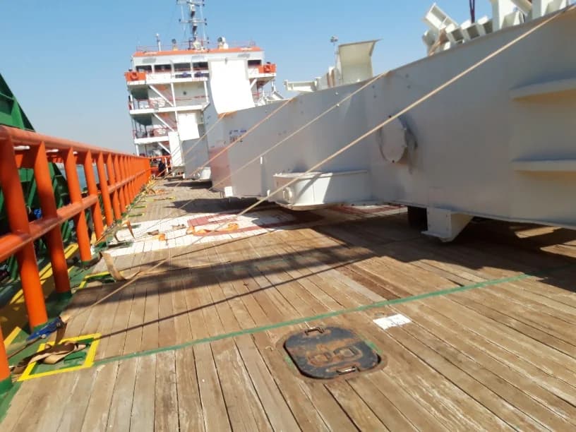 Long industrial structure lashed on the deck of a cargo vessel.
