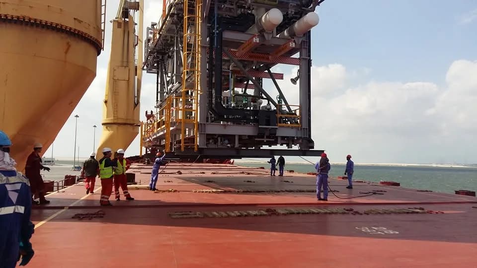 Large industrial equipment suspended above a vessel deck during a heavy lift.